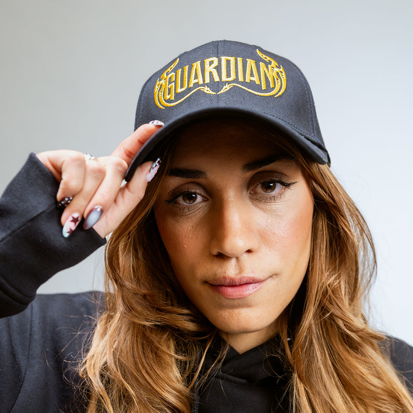 Woman wearing a Defqon.1 cap with 'Guardians' embroidered on it against a neutral background