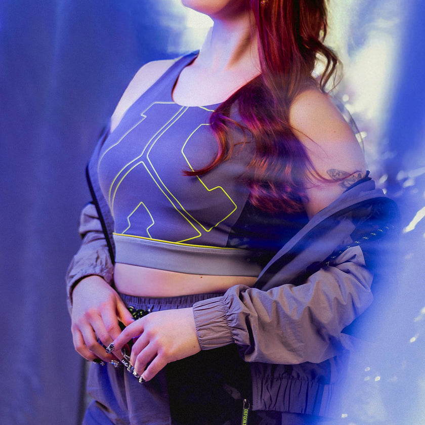 Person wearing a Defqon.1 sports bra and jacket with a blue and purple gradient background