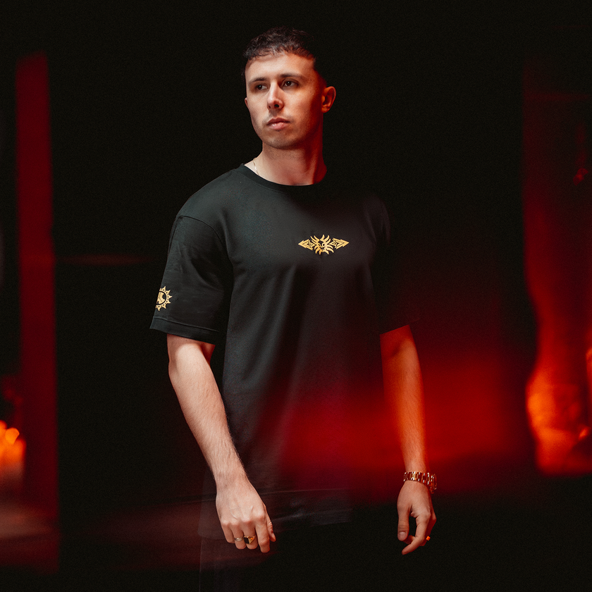 D-STURB wearing a Defqon.1 black t-shirt with a gold logo against a dark background